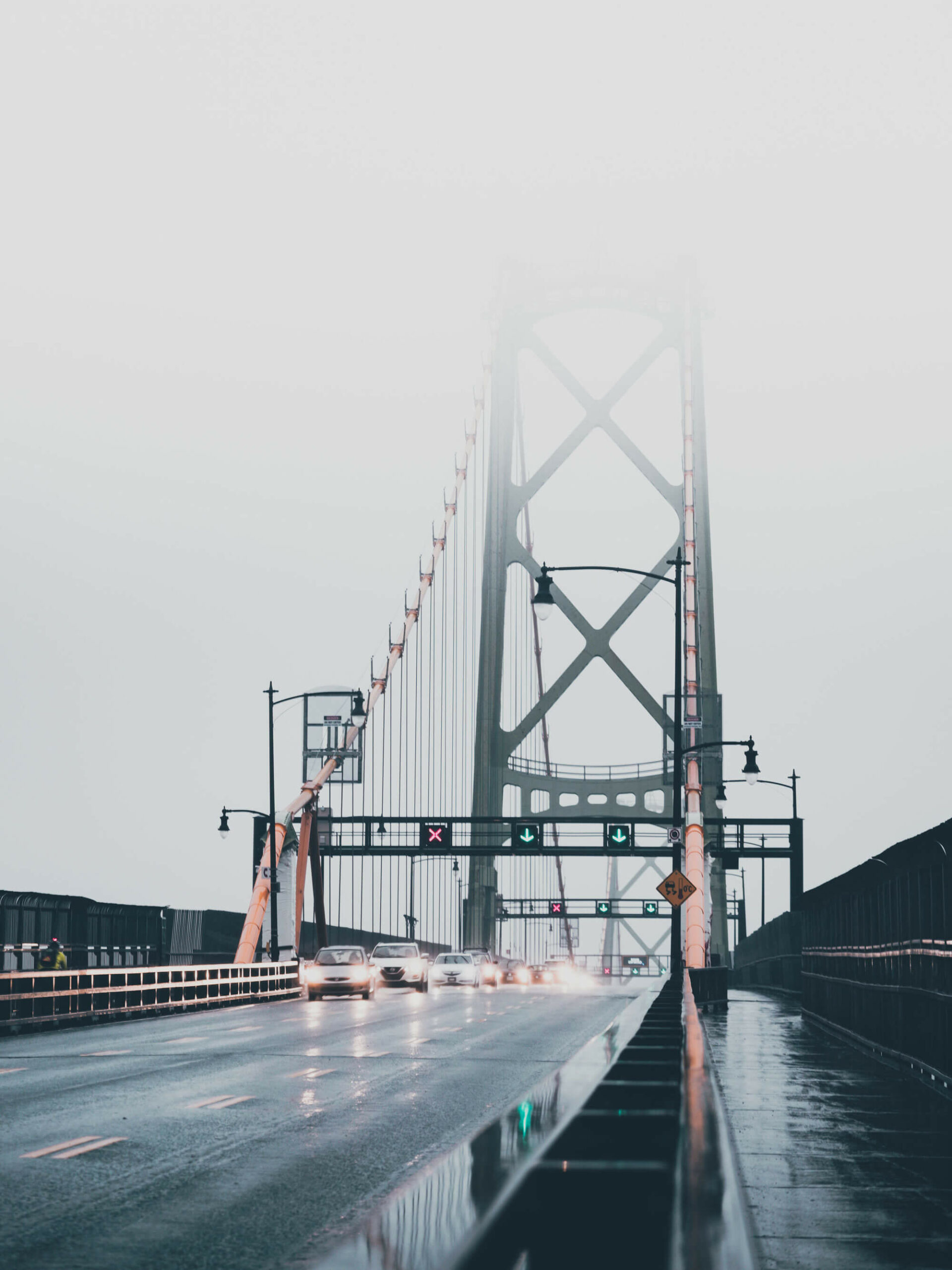 Street view of multiple incoming cars on the Macdonald Bridge that is partly covered by the fog.