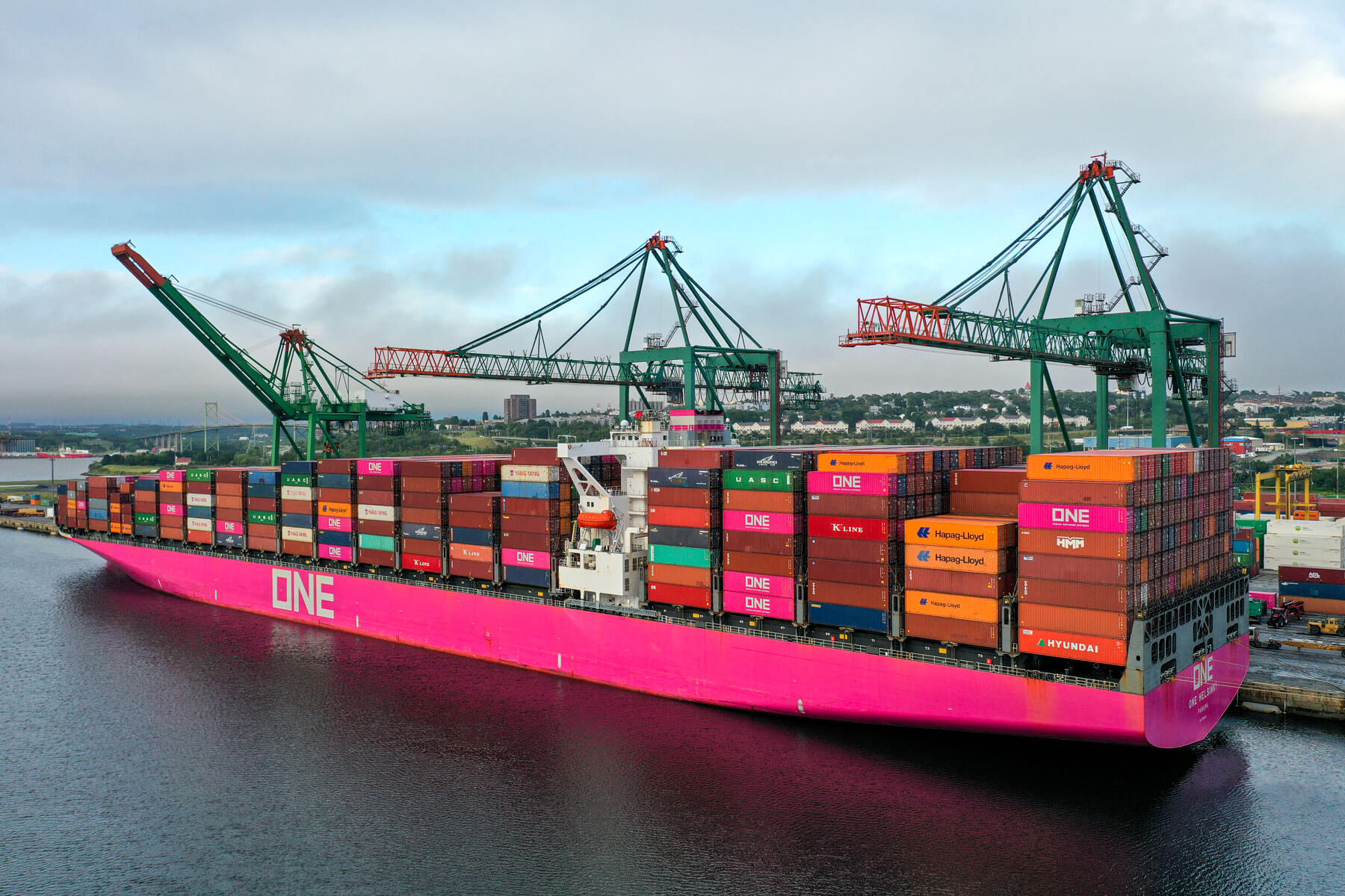 An aerial of ONE Helsinki, stacked three to four tall with brightly coloured shipping containers. Three large cranes are visible in the background.